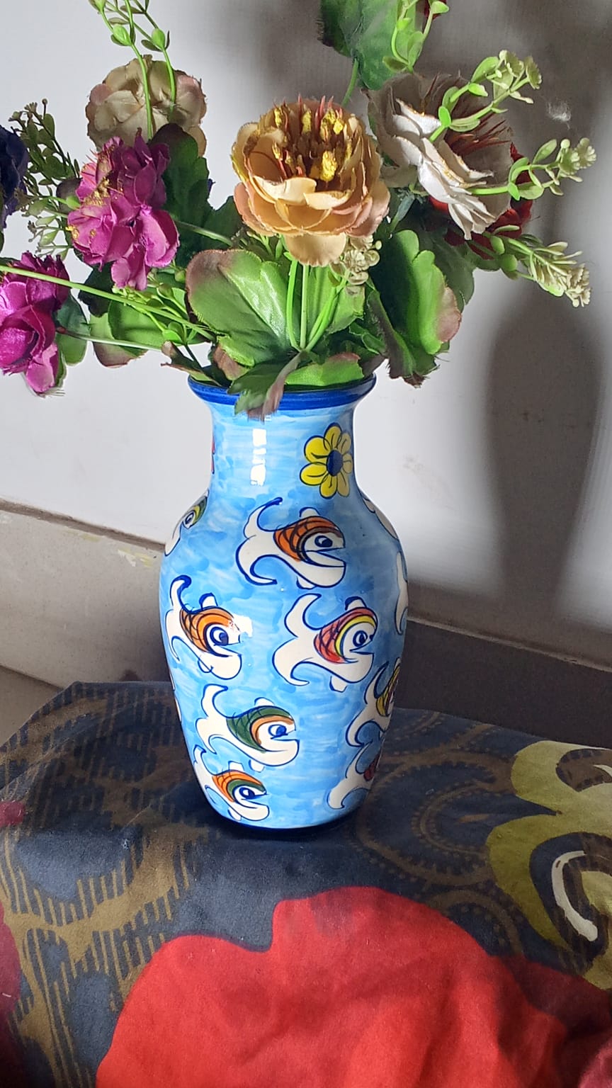 hand-painted ceramic vase holding a colorful arrangement of artificial flowers.