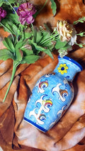 hand-painted ceramic vase holding a colorful arrangement of artificial flowers.