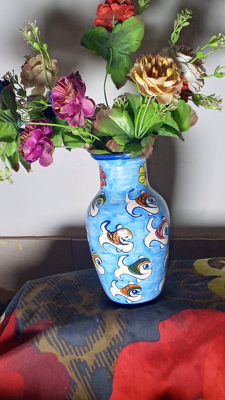 hand-painted ceramic vase holding a colorful arrangement of artificial flowers.